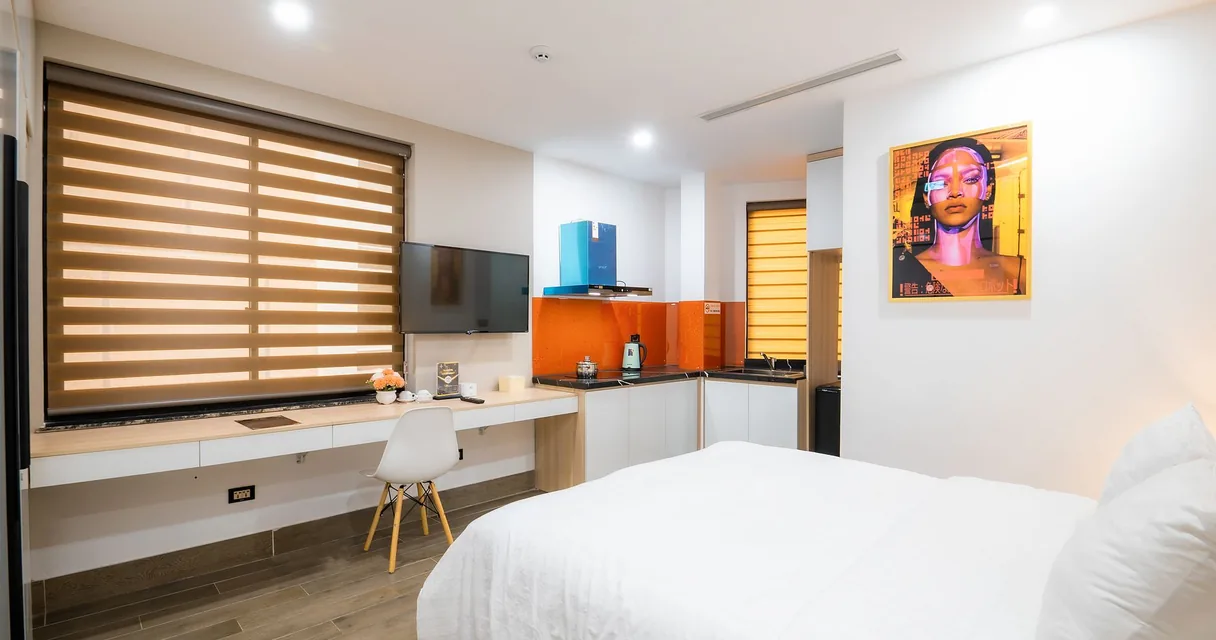 Quarto de hotel claro com cama, mesa de trabalho e televisão na parede, ilustrando a internet em pousada